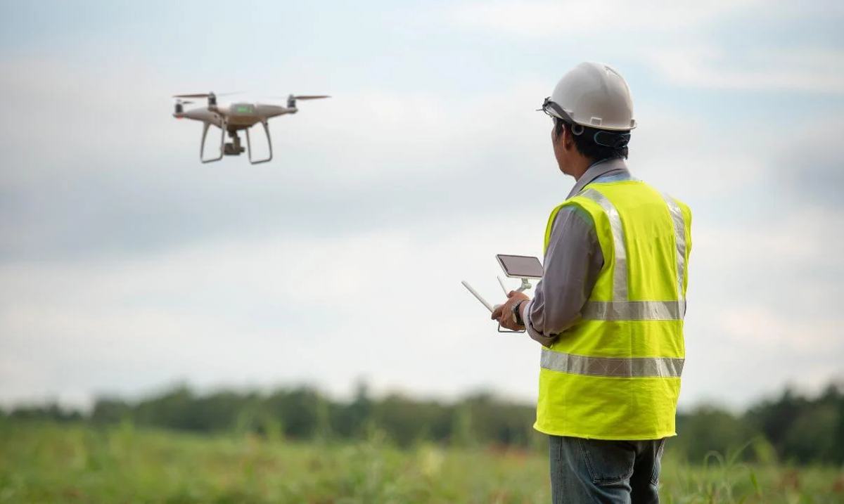 Surveyor flying a survey drone over an open site